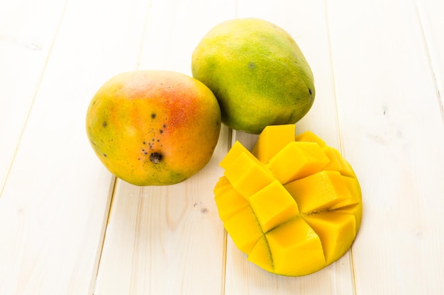 Fresh organic mango on a white wood board.