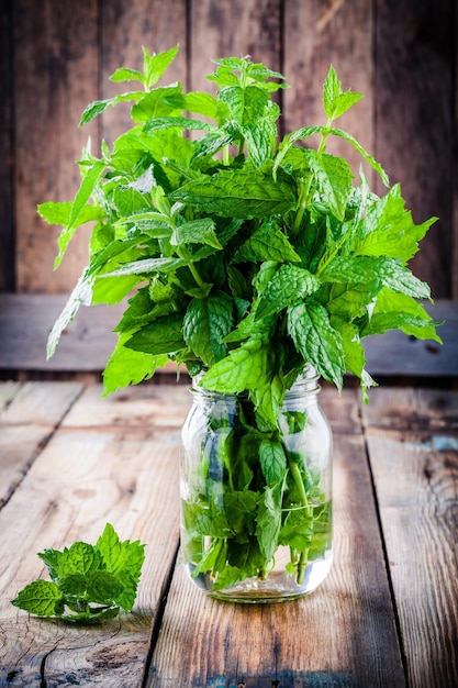 Fresh organic mint in glass on a wooden background