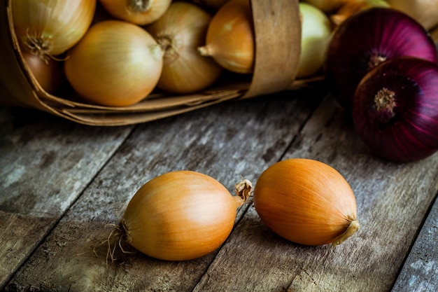 Fresh organic onions in a basket on a wooden background