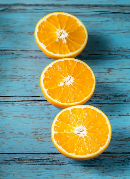 Fresh organic oranges halves fruits on blue wooden background with copy space