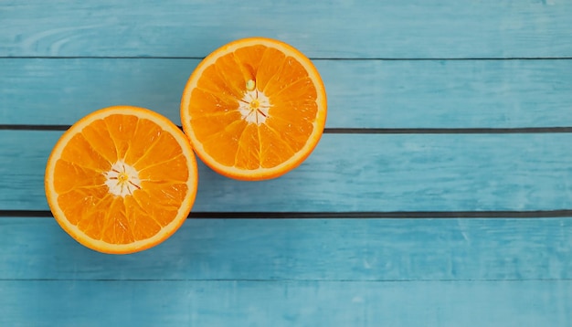 Foto arance organiche fresche dividono in due i frutti su uno sfondo di legno blu con spazio di copia