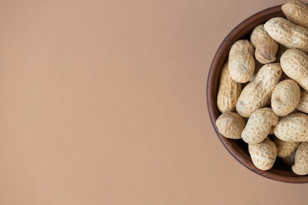 Fresh organic peanuts in the bowl on brown background