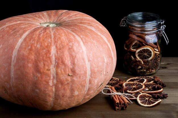 Fresh organic pumpkin and Christmas spices in a glass jar on a dark background