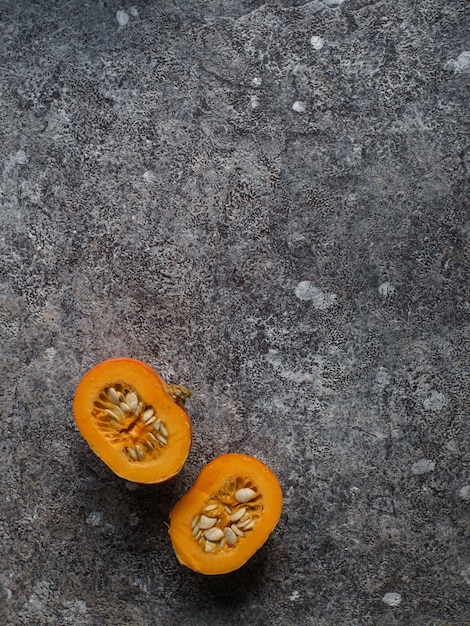 Fresh organic pumpkin in slices on dark stone table