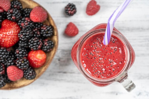 Fresh organic red smoothie in glass mug on white table close up top view Refreshing summer fruit drink Blackberry raspberry and strawberry smoothie