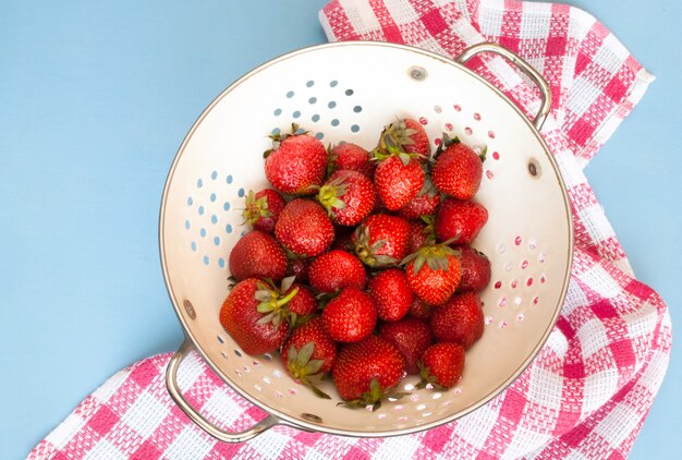 Fresh organic strawberries in a colander. top view
