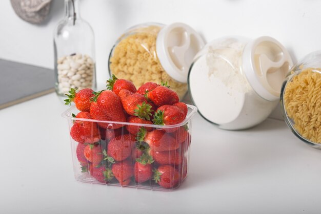 Foto fragole fresche biologiche in una scatola di plastica in cucina. consegna di prodotti biologici.