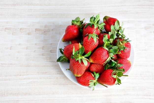 fresh organic strawberry on white plate on beige background, close-up