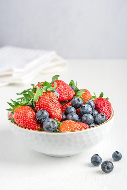 Fresh organic summer berries with juicy texture and sweetness served in bowl on white wooden table