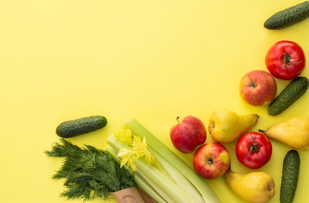 Fresh organic vegetables, greens and fruits on a yellow background. Ecological farm food concept. Top view. Flat lay.