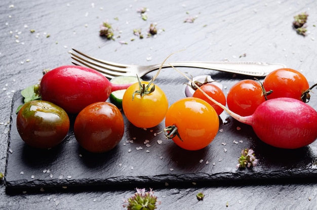 Fresh organic vegetables on slate stone tray with spices aside closeup dark concept photo