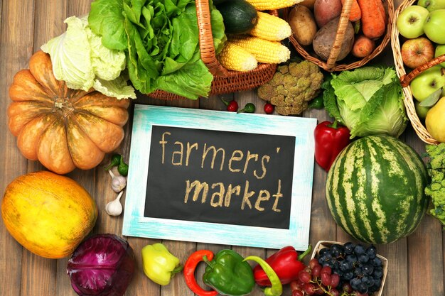 Fresh organic vegetables with chalkboard on wooden table close up