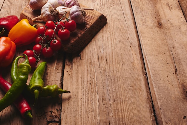 Fresh organic vegetables on wooden board close up. Cherry tomatoes, garlic, peppers and dill on a wooden table.