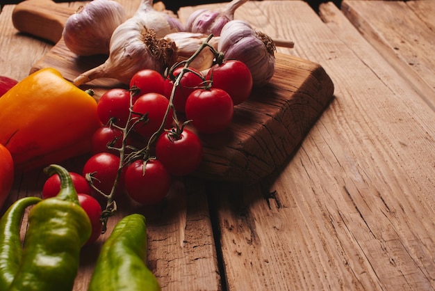 Fresh organic vegetables on wooden board close up. Cherry tomatoes, garlic, peppers and dill on a wooden table.