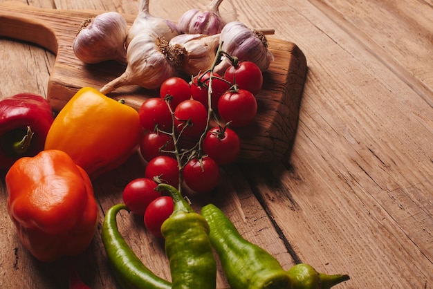 Fresh organic vegetables on wooden board close up. Cherry tomatoes, garlic, peppers and dill on a wooden table.