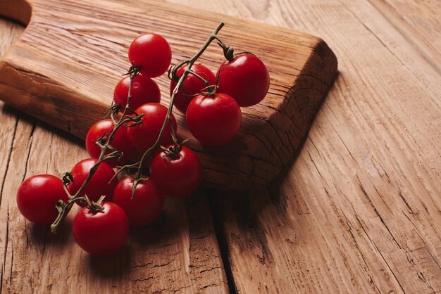 Fresh organic vegetables on wooden board close up. Cherry tomatoes, garlic, peppers and dill on a wooden table.