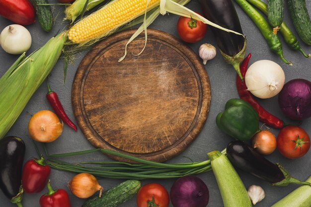 Fresh organic vegetables and wooden board with copy space background Healthy natural food Tomato corn pepper eggplant chilli and other cooking ingredients top view