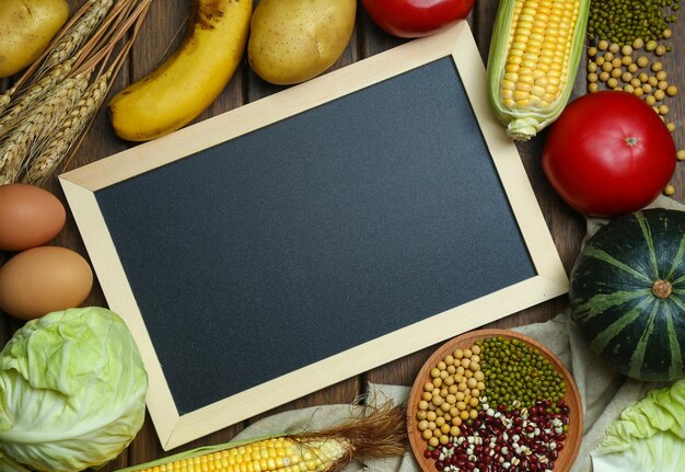 Fresh organic vegetablesfruitseggsbeansand corns with blackboard on vintage wooden table