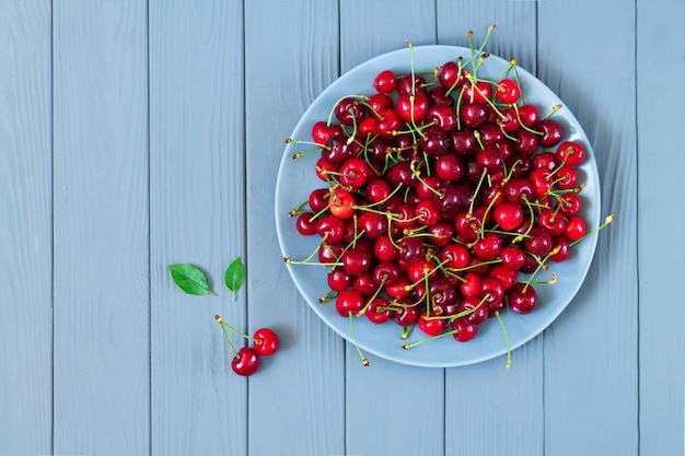 Fresh organic wet sweet cherry on plate on wooden table top view