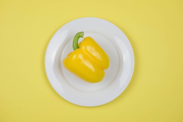 Fresh organic yellow pepper on a white plate