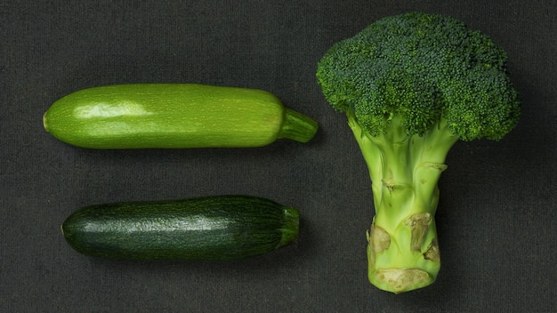 Fresh organic zucchini and broccoli closeup on a dark background top view