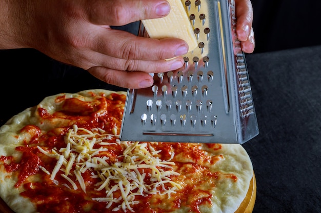 Fresh original Italian raw pizza, preparation in traditional making pizza male hands on pi