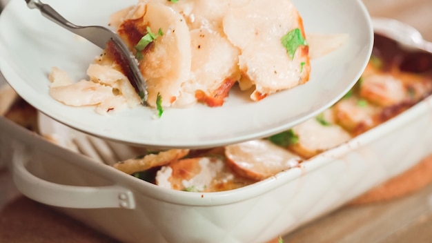 오븐에서 갓 구운 가리비 감자를 흰색 세라믹 베이킹 접시에 파슬리로 장식합니다.