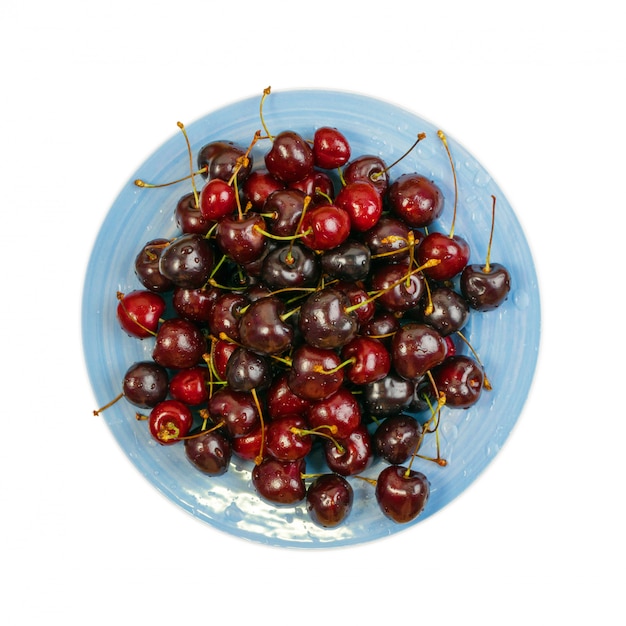 Fresh Overripe ripe Cherries on Blue Rustic Plate Top View