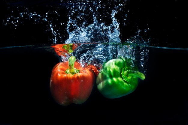 Fresh Paprika Chilies splashing into clear water splash 