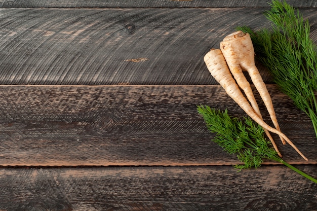 Foto radice e pastinache fresche di prezzemolo su fondo di legno