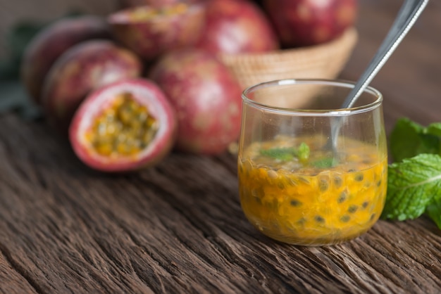 Photo fresh passion fruit in glass and organic passionfruit on wooden background.