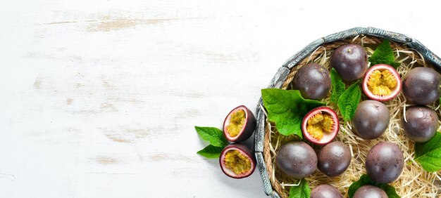 Fresh passion fruit with leaves in Wooden Box. Tropical Fruits. Top view. Free space for text.