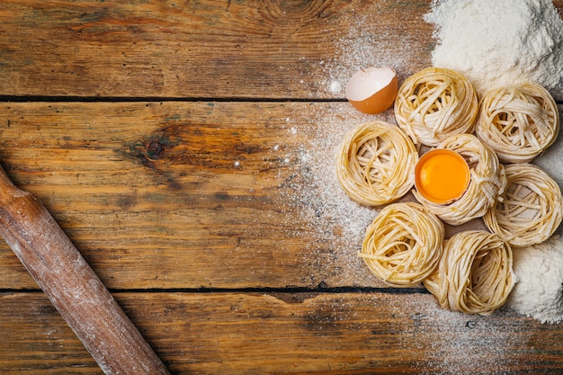 Alimenti per pasta fresca. pasta italiana fatta in casa cotta su un tavolo di legno in stile rustico decorato con uova e farina.