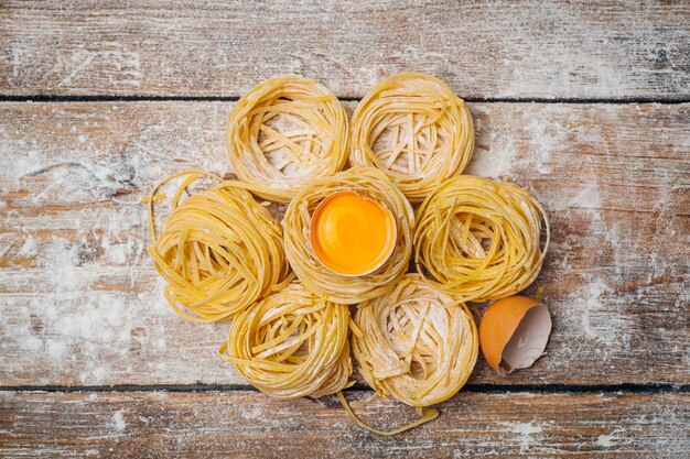 Fresh pasta food. Homemade Italian pasta cooked on a wooden table in a rustic style decorated with egg and flour.