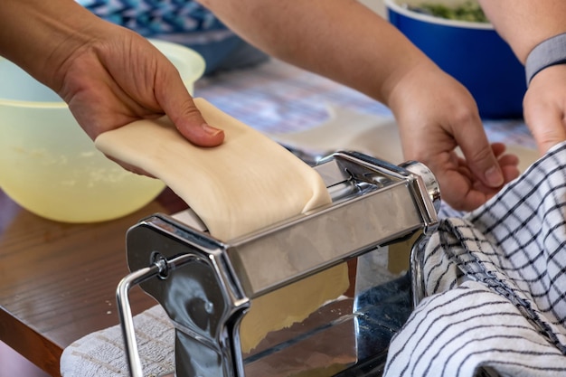 Свежая паста домашнего приготовления Руки работают на кухне машина для производства макаронных изделий крупным планом
