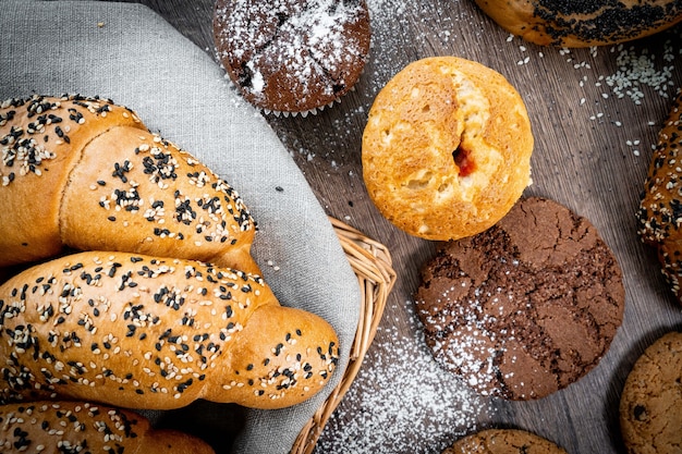 Panini di pasticceria fresca nel cestino in panetteria in stile rustico con grano bianco sulla tavola di legno