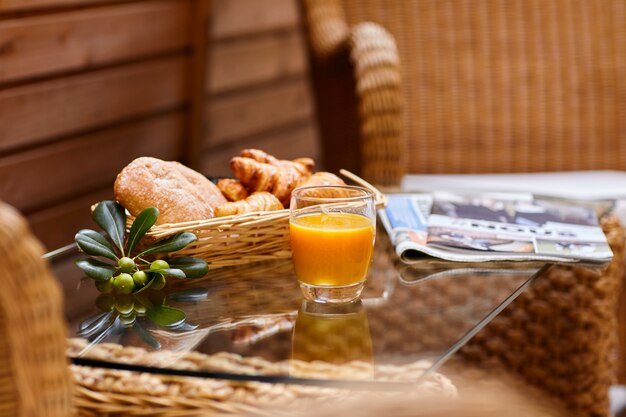 Fresh pastries, orange juice, olive branch and fresh newspaper on the table for breakfast