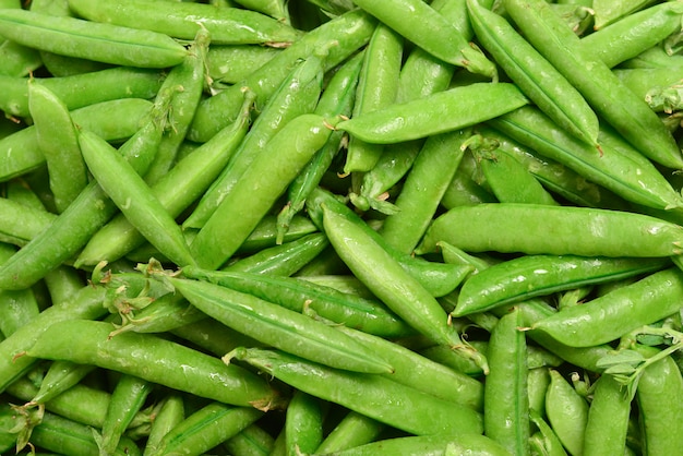 Fresh pea pods as background. Top view.