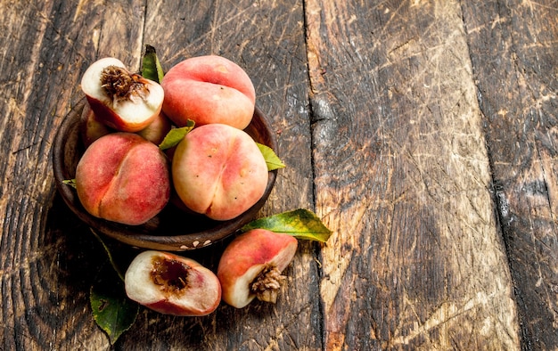 Fresh peaches in a bowl. On a wooden background.