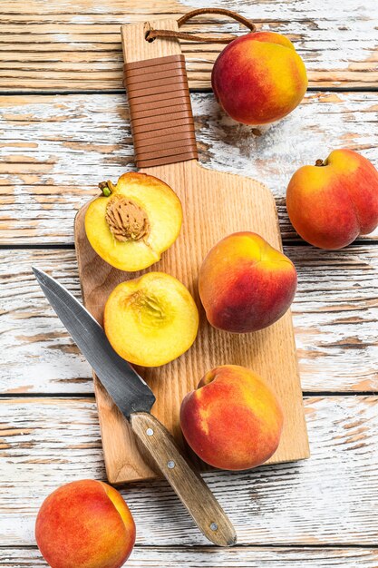 Fresh Peaches, organic fruit on the chopping Board on White wooden table. 