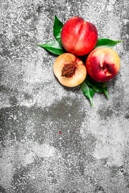 Fresh peaches with green leaves. On rustic table.