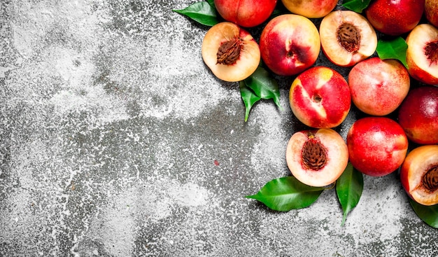 Fresh peaches with green leaves. On rustic table.