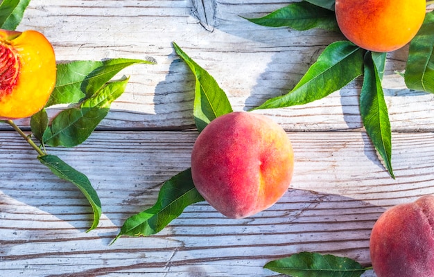 Fresh peaches with leaves on a wooden background. Summer time.