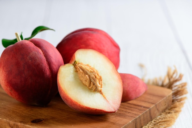 Fresh peaches on wood plate and white background Peaches are widely eaten fresh