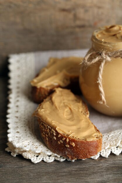 Fresh peanut butter in jar on wooden background