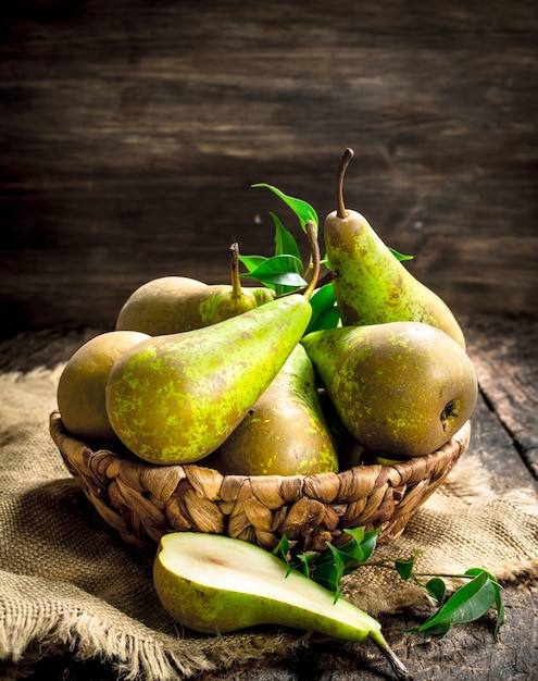 Pere fresche in un canestro. su uno sfondo di legno.