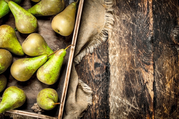 Fresh pears onn old tray on wooden table.