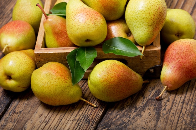 Fresh pears with leaves in a box on wooden table