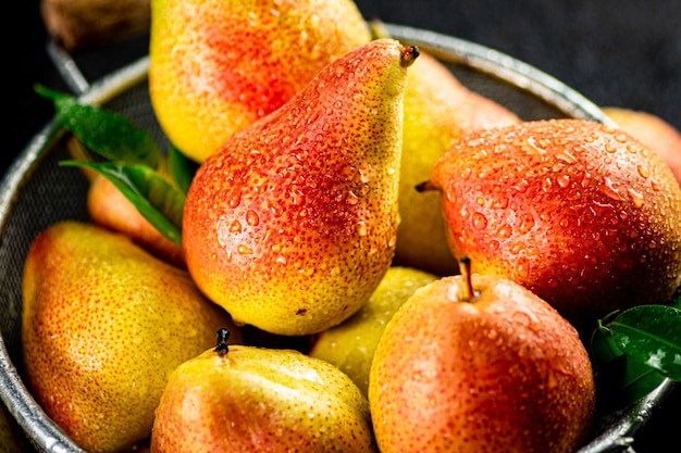 Fresh pears with leaves in a colander