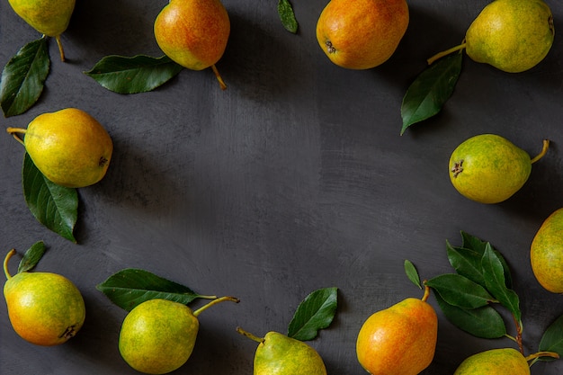 Fresh pears with leaves on a gray table